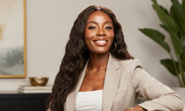 AJ Odudu smiling in a beige blazer during an indoor portrait shoot