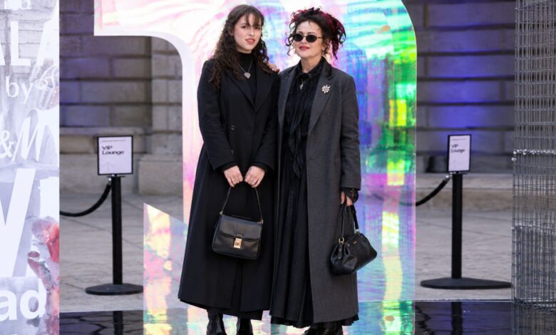 Nell Burton and Helena Bonham Carter posing together at a fashion event in full-length covered outfits